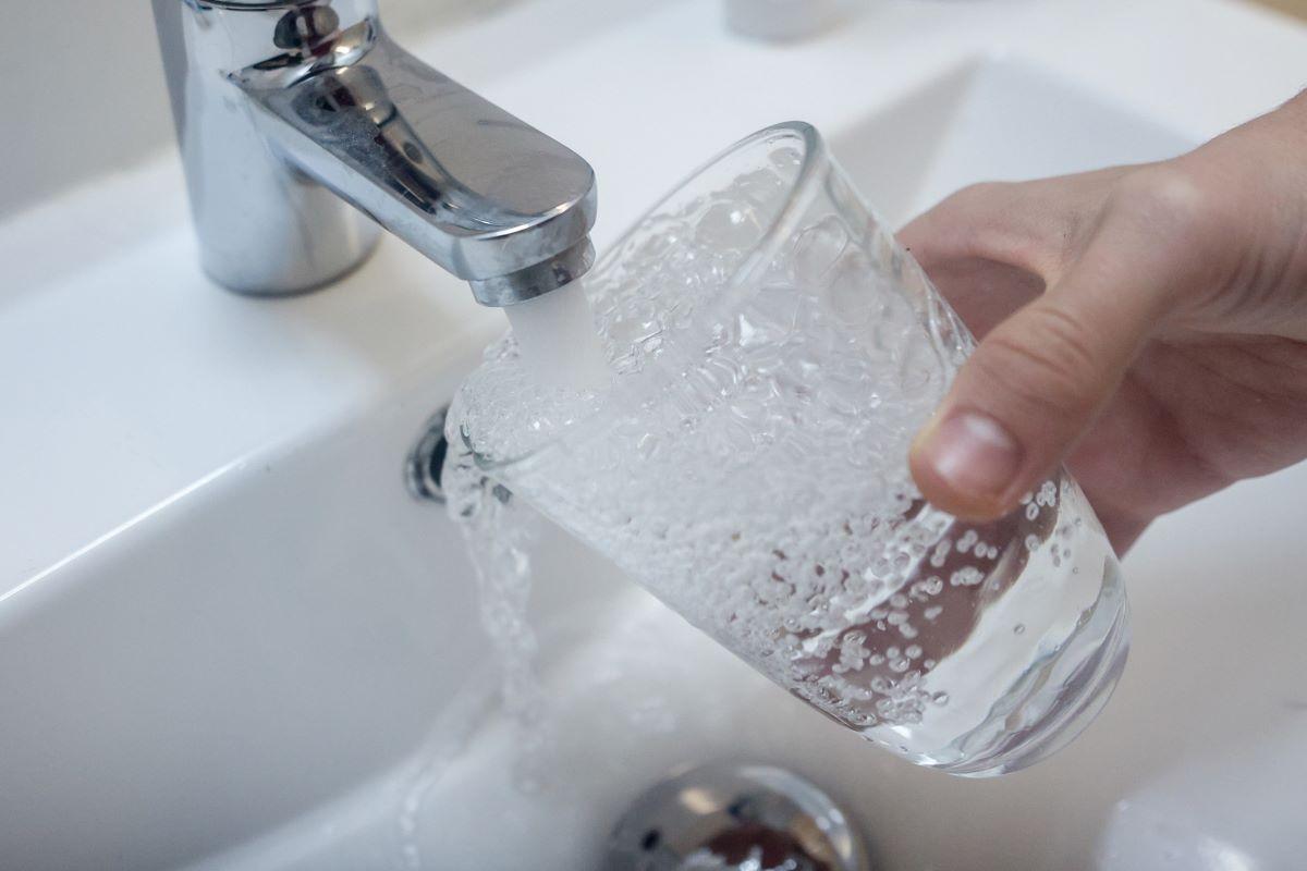 Persona llenando vaso con agua del grido.