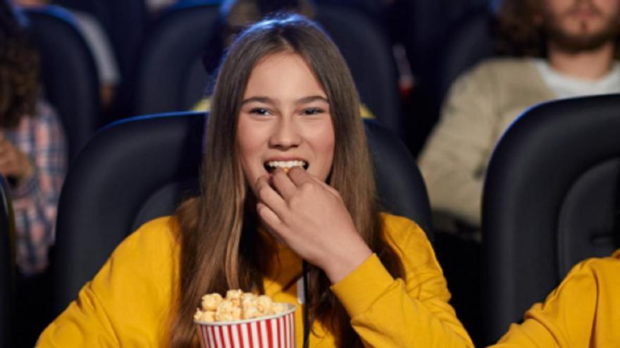Una joven toma palomitas en el cine.