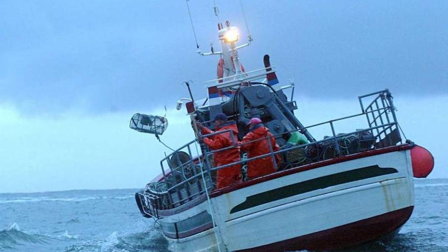 Un marinero de un pesquero gallego lanza nasas al agua en alta mar.