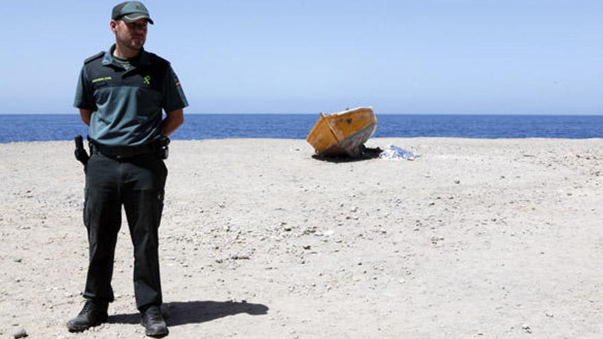 Un agente de la Guardia Civil custodia el cuerpo que yace junto a la barca. | s. pérez