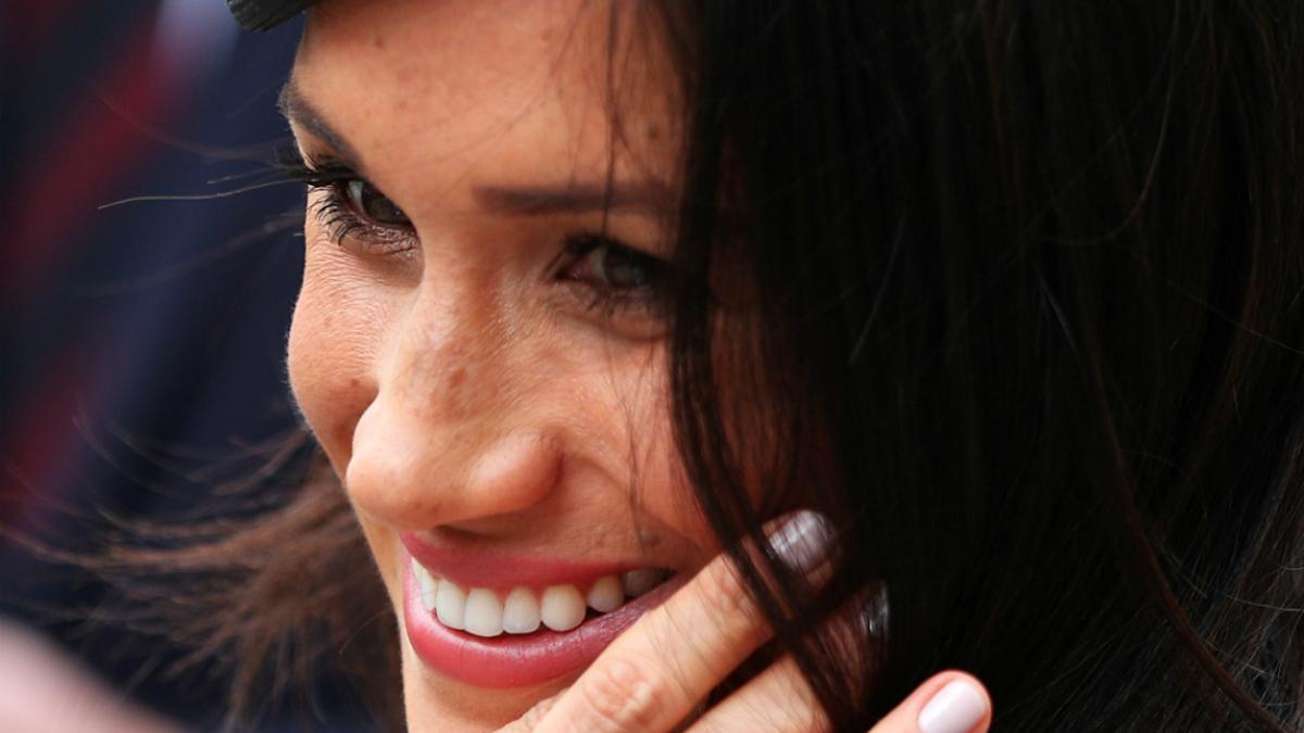 Meghan Markle sonriente se aparta el pelo de la cara