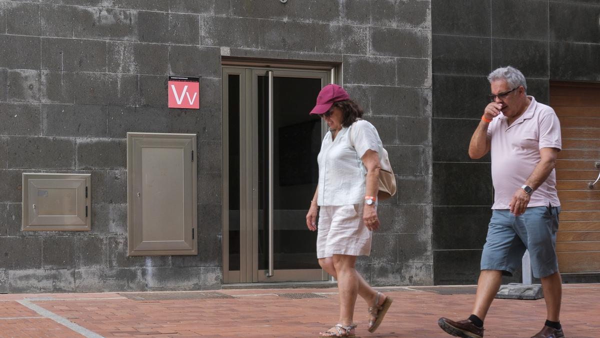 Una pareja pasea por delante de una vivienda vacacional.