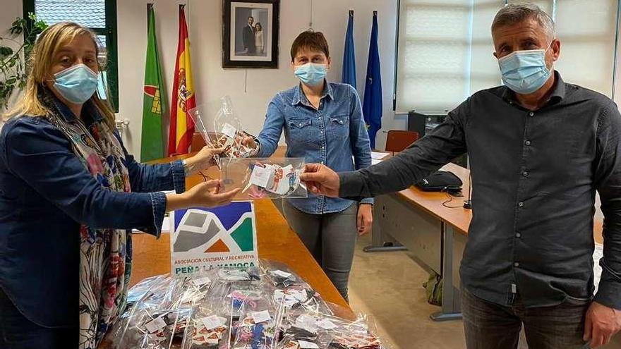 Covadonga Fernández, a la izquierda, entrega las mascarillas infantiles a Tensi Carmona y a Marcelino Martínez.