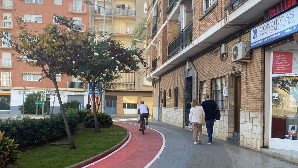 Un ciclista recorre el carril bici junto a dos peatones, este viernes en Paiporta