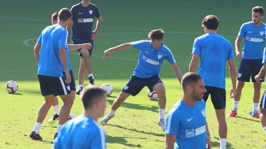 Los jugadores del Málaga, con Mula al frente y ante la atenta mirada de Muñiz, realizan un rondo durante un entrenamiento reciente.