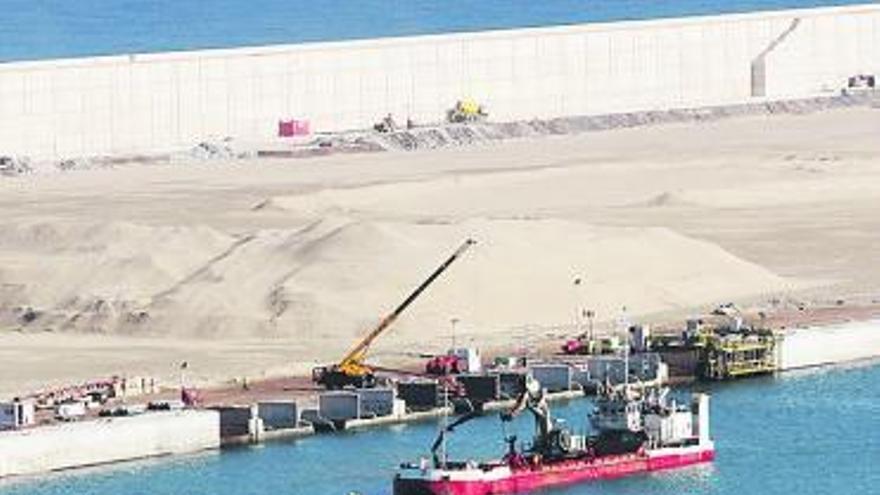 Al fondo de la foto, sobre el nuevo muelle Norte de El Musel, la arena en principio destinada a regenerar la playa de San Lorenzo y ahora desechada.