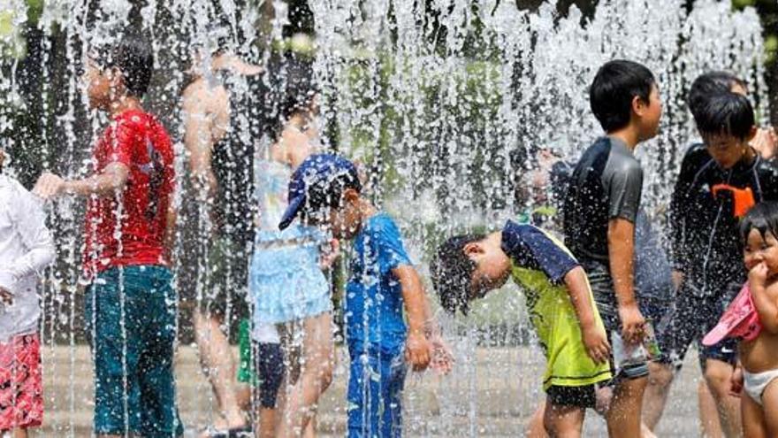 Niños japoneses se refrescan en una fuente.