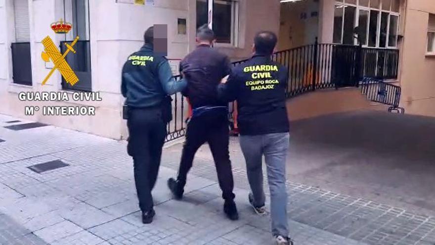 Dos agentes trasladan a la comandancia de Badajoz a uno de los detenidos.