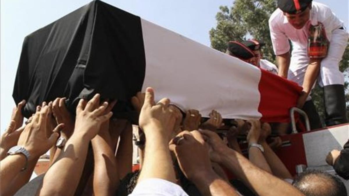 Un féretro con los restos de un policía muerto en los disturbios del miércoles es trasladado por sus compañeros, durante los funerales celebrados este jueves en El Cairo.