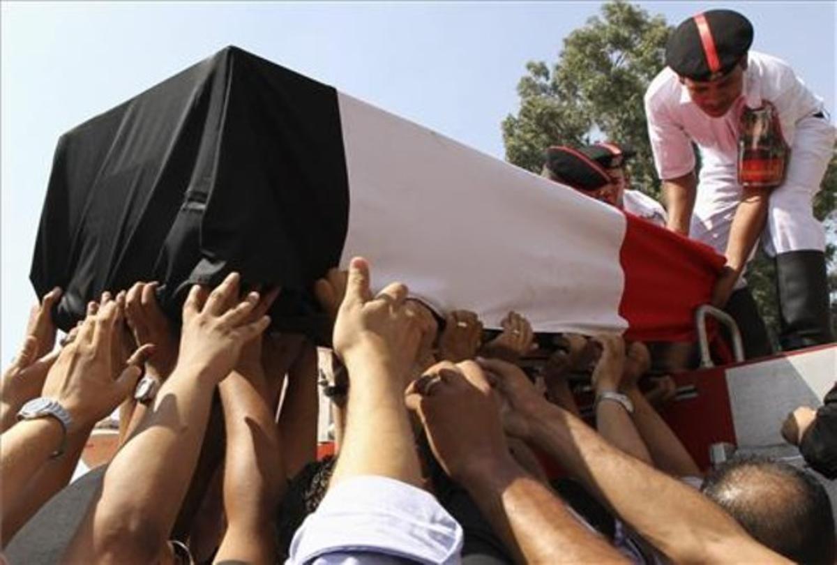 Un fèretre amb les restes d’un policia mort en els disturbis de dimecres és traslladat pels seus companys, durant els funerals celebrats aquest dijous al Caire.