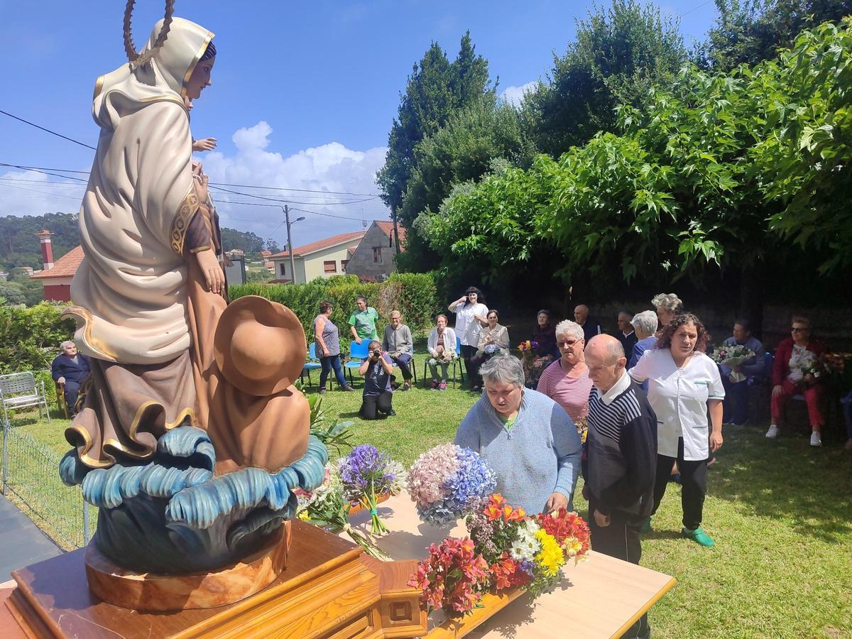Los mayores del centro de día Sanidía, en Darbo, depositan ramos de flores ante la imagen del Carmen.