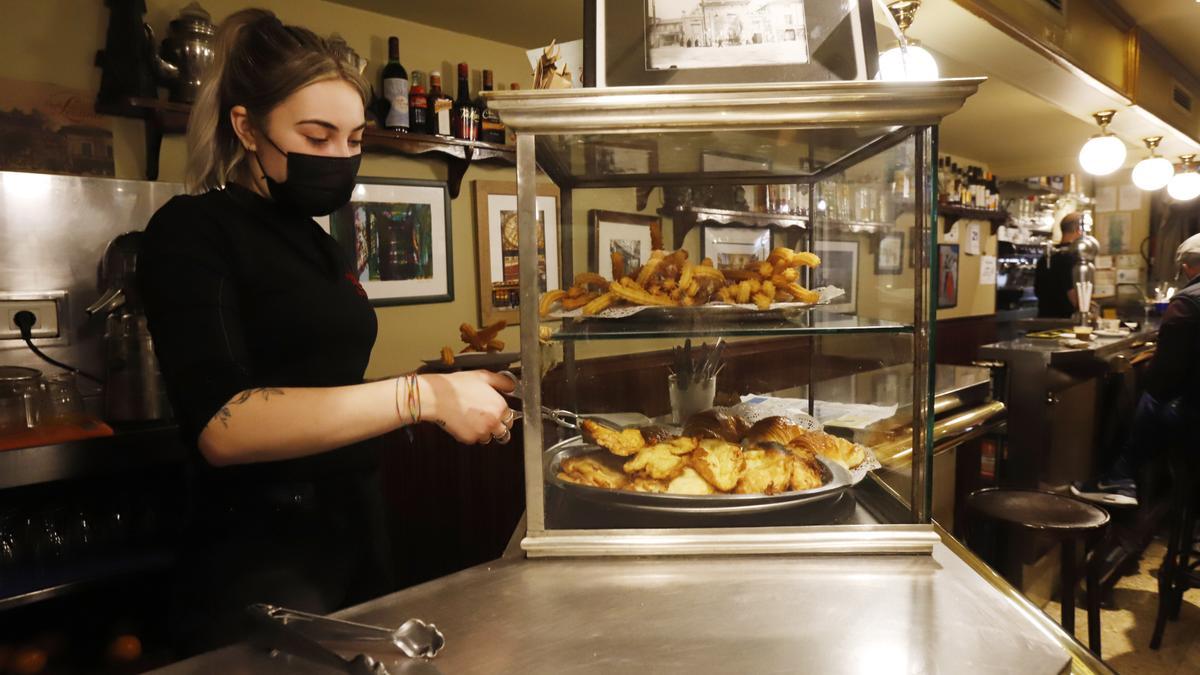 La camarera del Café Levante sirve unos churros, que cocinan ellos mismos y cuyas materias primas (harina y aceite) han triplicado su precio en los últimos días.