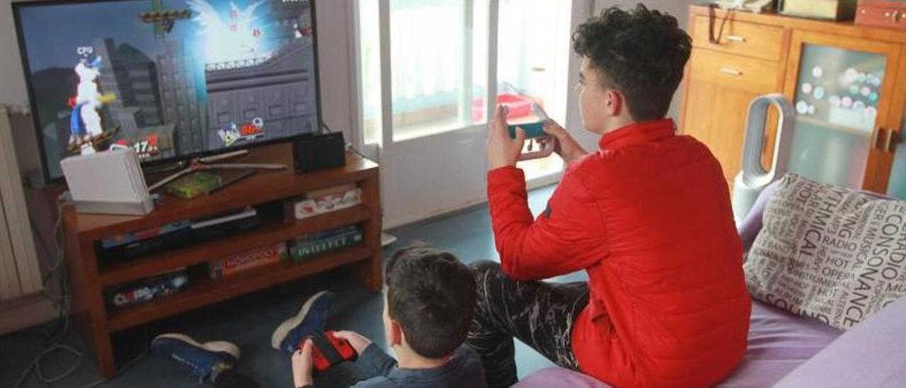 Dos menores se entretienen con videojuegos en su casa.