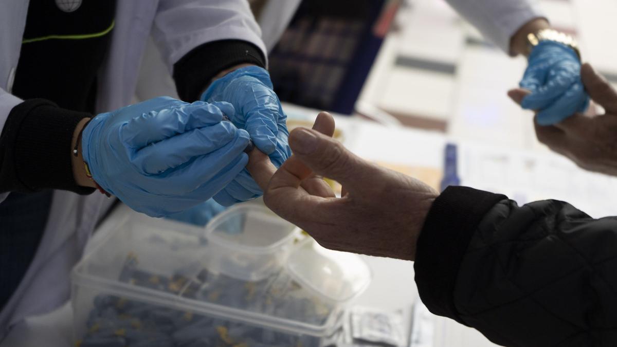 Una enfermera pinchando a un paciente para medir el nivel de glucosa