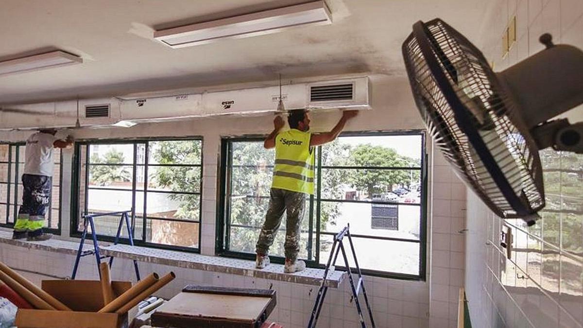 Unos operarios trabajan en la climatización de un colegio.