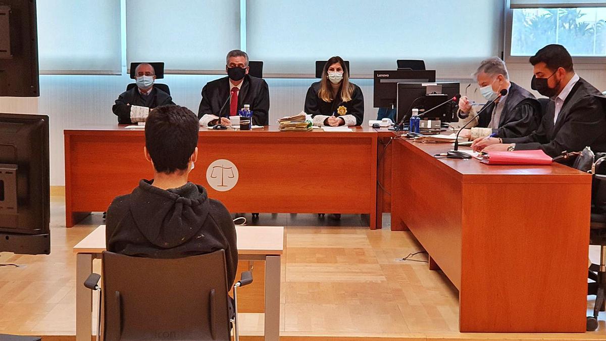 El joven que apuñaló a su compañero de clase, de espaldas ayer en el juicio celebrado en Elche.