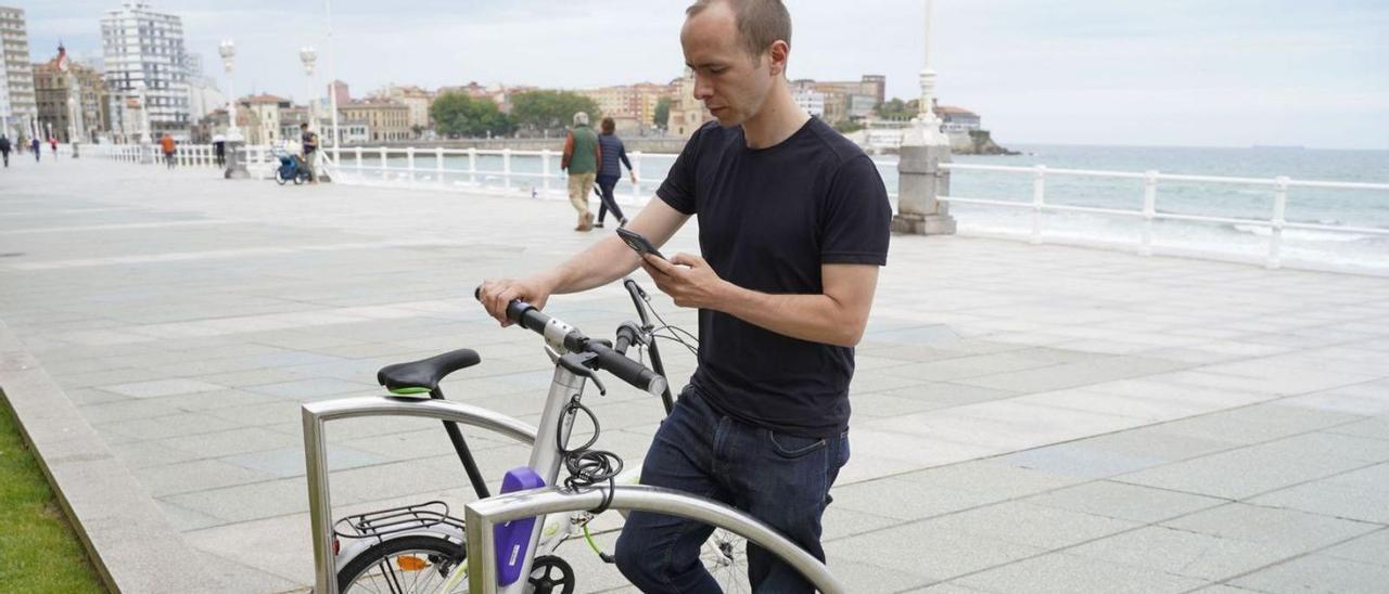 Darío Abad, ayer, subiéndose en el paseo del Muro a uno de los nuevos patinetes con intermitentes en los manguitos del manillar.