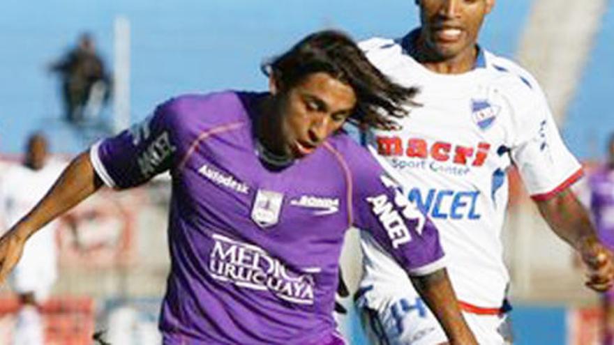 Damián Suárez conduce el balón perseguido por un rival.