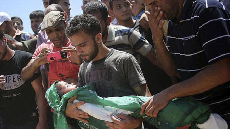Varios palestinos entierran a un niño muerto en los bombardeos.