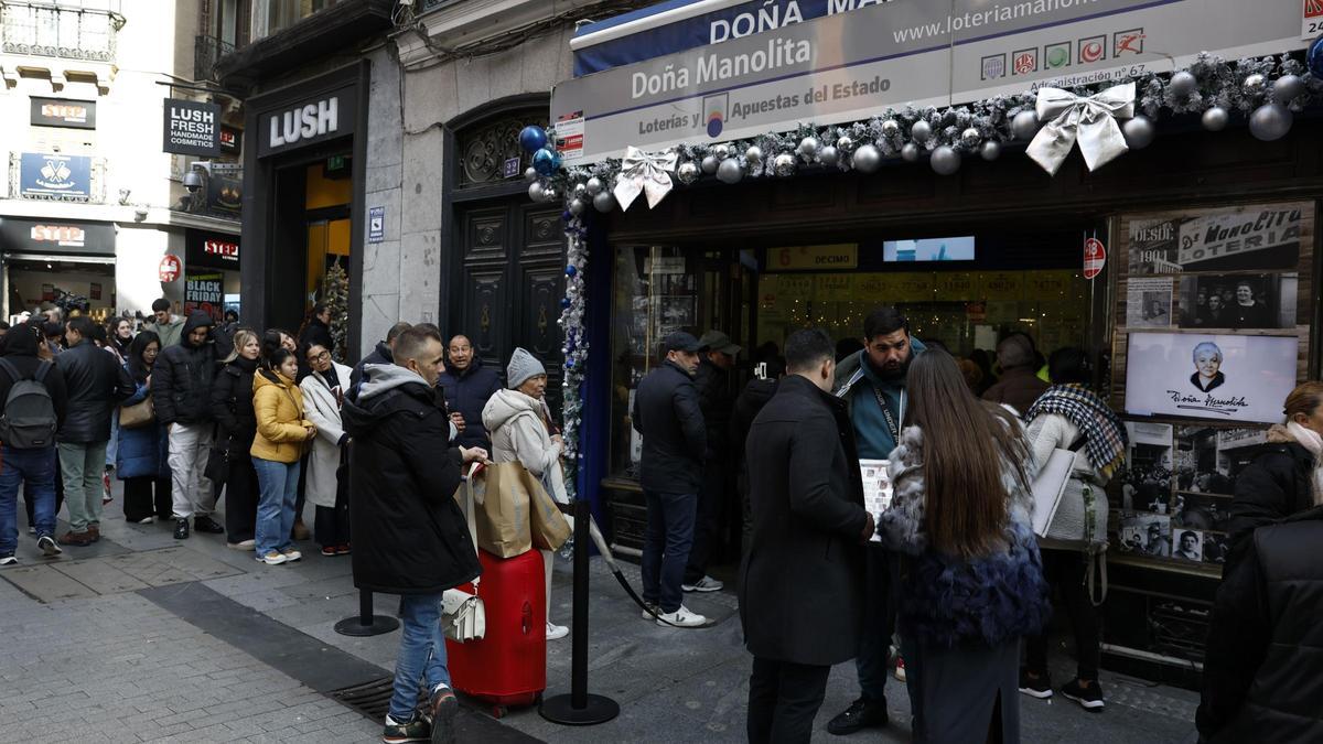 Varias personas hacen cola en una despacho de Lotería.