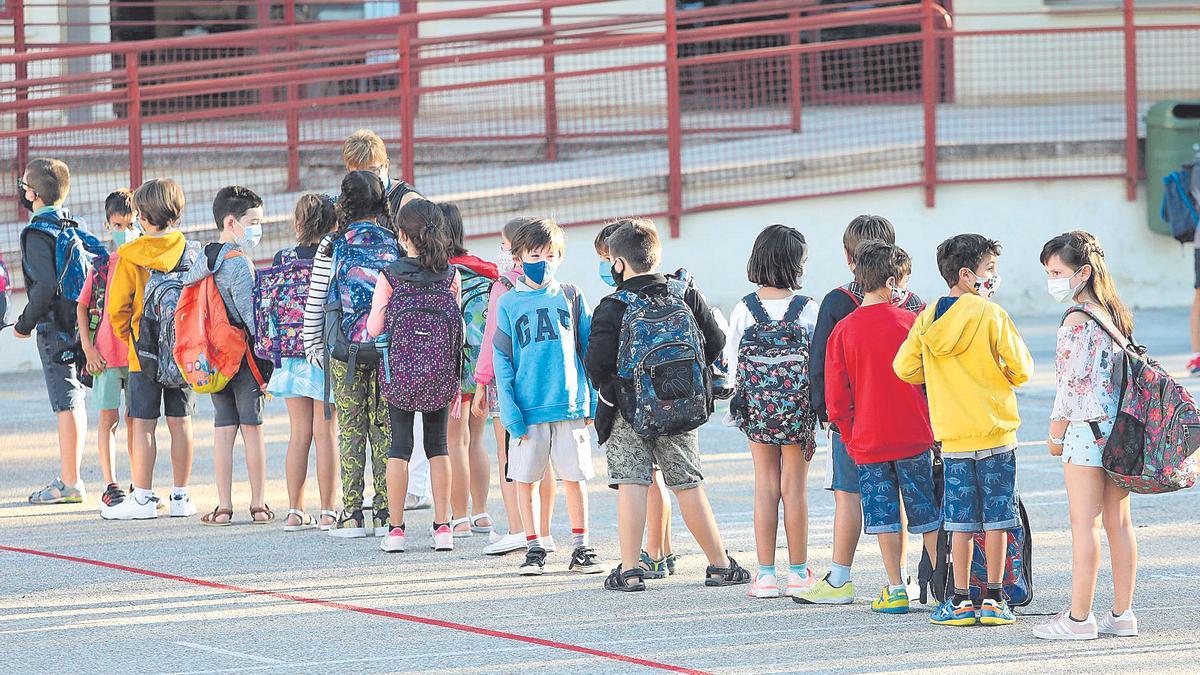 Varios alumnos, protegidos con mascarilla, esperan en la fila para acceder a clase en un colegio zaragozanos, este curso.