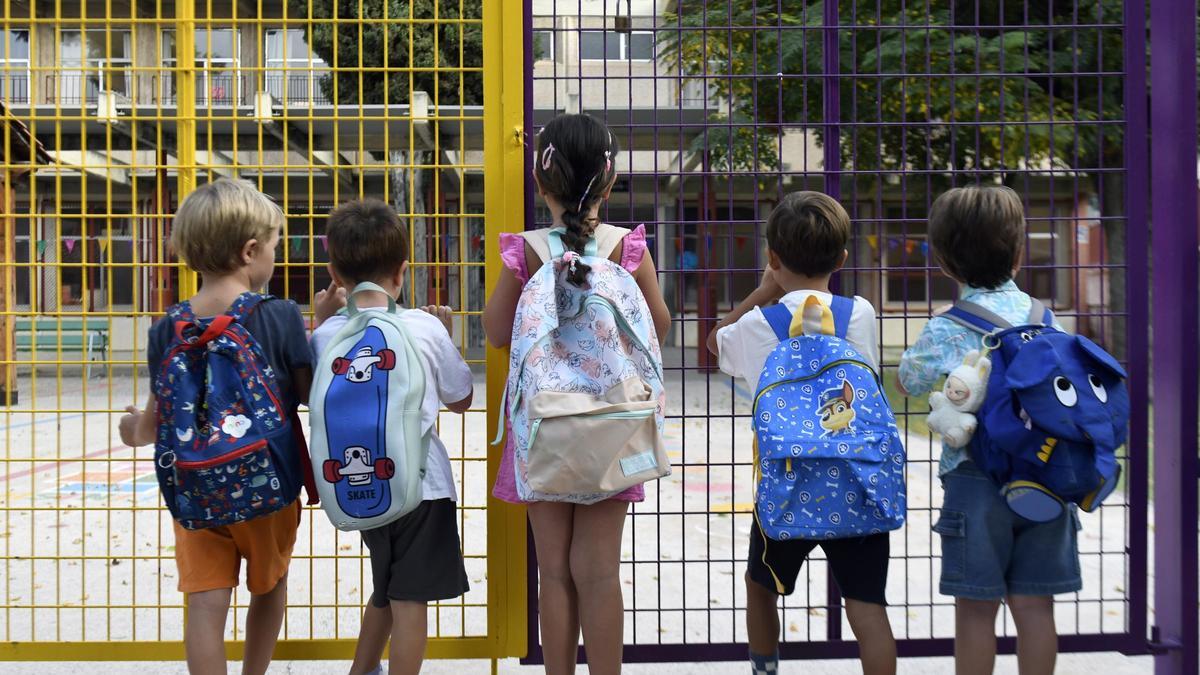 Cinco pequeños se asoman a su colegio, el CEIP Mariano Aroca López.