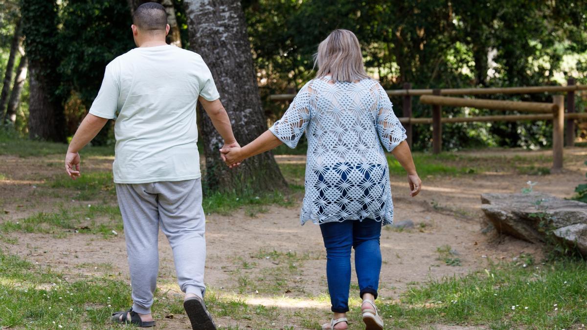 Adrià Lorente, un chico con autismo, pasea por un parque de Cardedeu con sus padres Eva Velàzquez y José Antonio Lorente