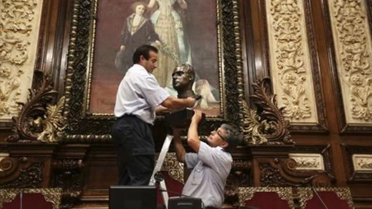 Operarios del Ayuntamiento de Barcelona retiran el busto del rey Juan Carlos del salón de plenos municipal y lo guardan en una caja de cartón.