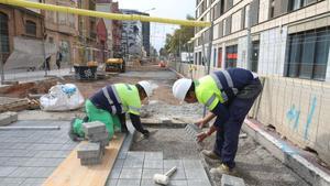 Personal trabaja en el pavimento de la acera de una calle en Barcelona