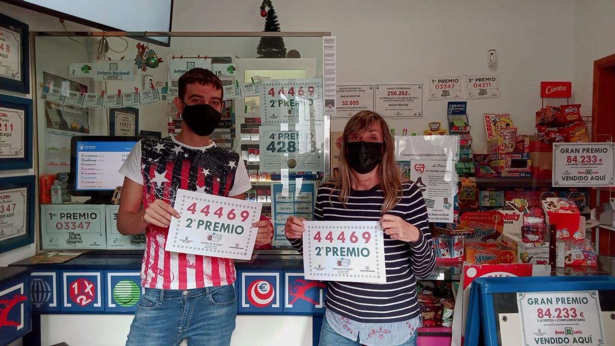 Ricardo Ramos y Montse de la Cruz en el Bazar Montse en Yaiza con los carteles del segundo premio de la Lotería del Niño