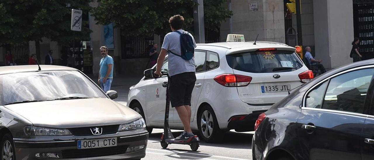 Un usuario de patinete eléctrico circulando por la calzada.