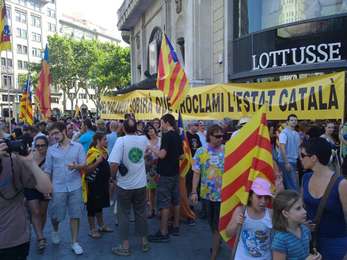 Numerosos ciudadanos aguardan el inicio de la marcha en uno de los laterales de paseo de Gràcia. 