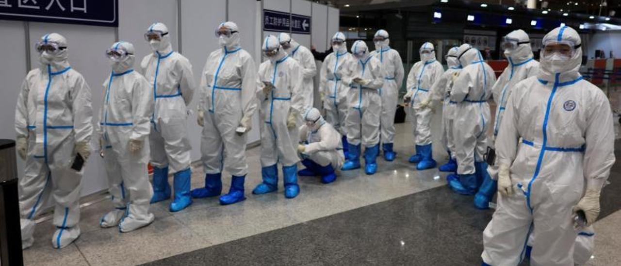 Personal del aeropuerto de
Pekín con trajes protectores,
contra el COVID, el pasado 
lunes.   | // WOLFGANG RATTAY