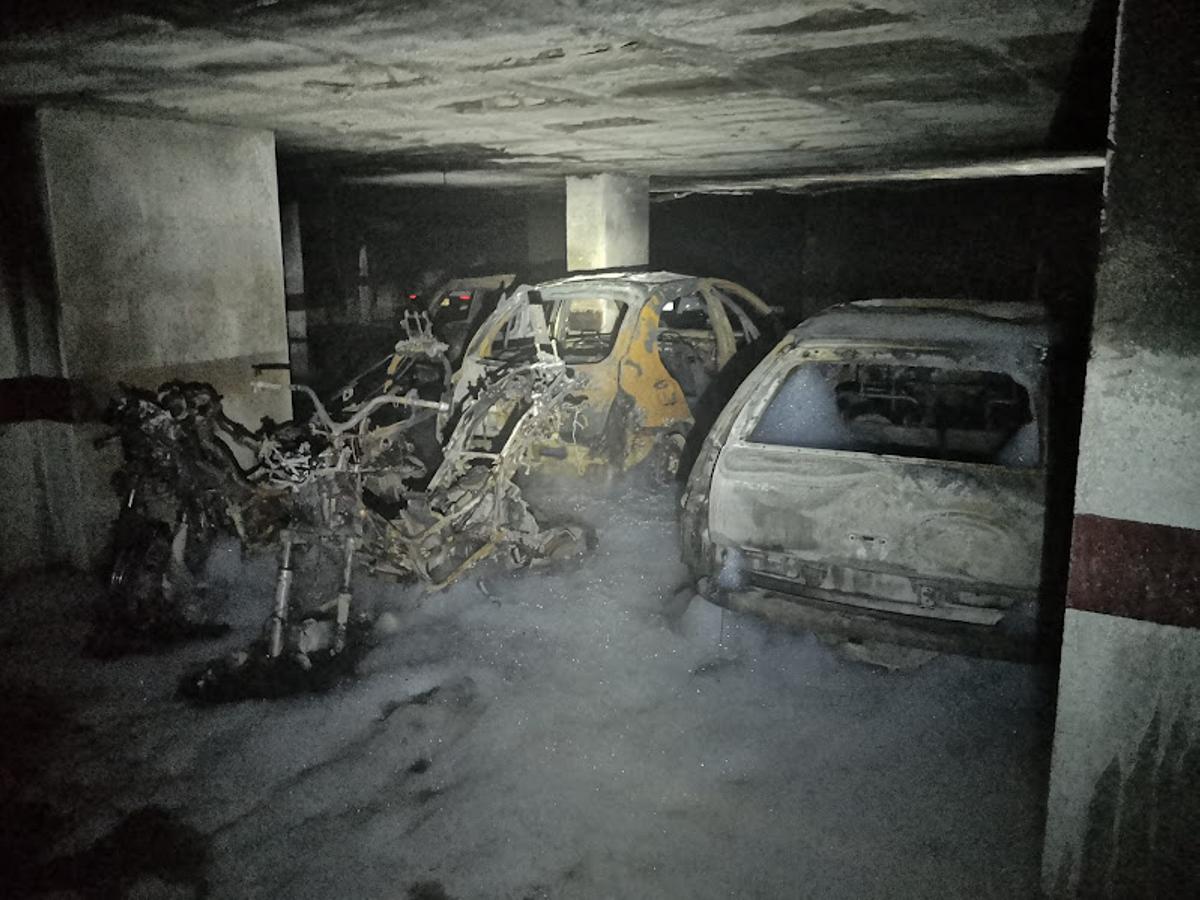 Estado en el que quedaron los coches y motos estacionados en uno de los aparcamientos incendiados.