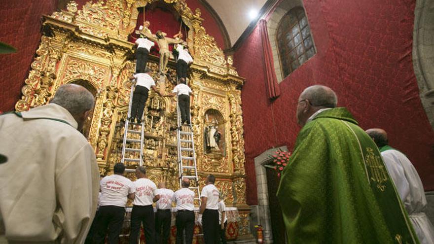 Los mayordomos bajan al Cristo de Telde desde la hornacina y el claretiano Vicente Cuadrado de verde.