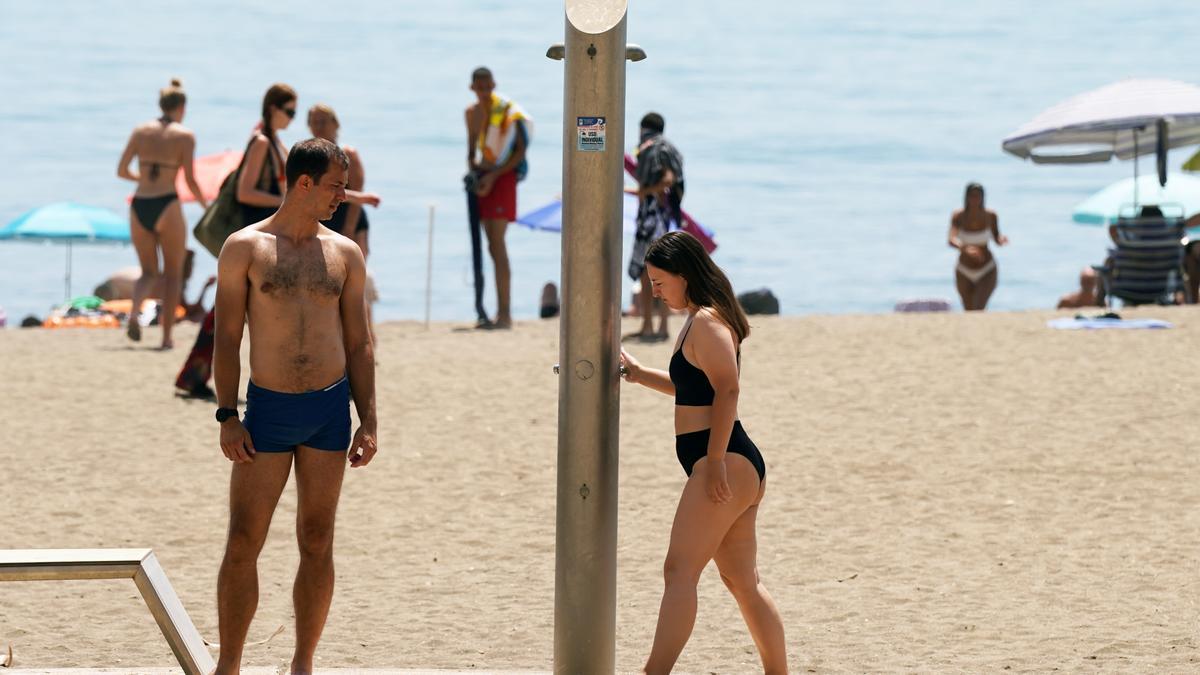 Dos personas comprueban el corte de agua en las duchas de la playa en La Malagueta