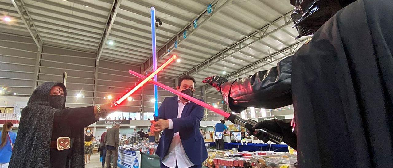 Barriss Offee (María José Magdalena), Miguel Martínez y Darth Vader (José Pérez), luchan con espadas láser ayer, en la inauguración de la Feria del Coleccionismo. | C. M. B.