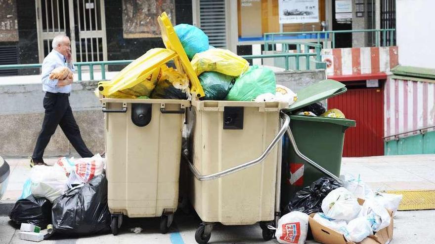 Bolsas de basura acumuladas en contenedores en una calle de la ciudad.