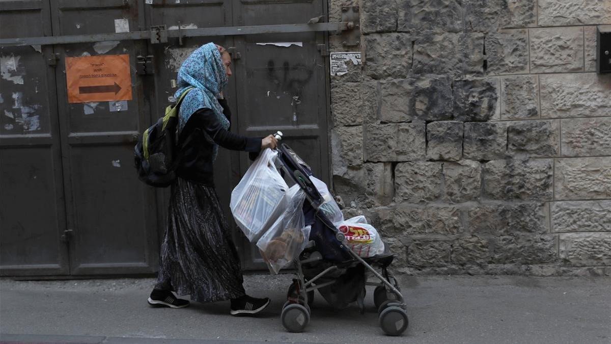 Una judía ultraortodoxa camina por Jerusalén con un carrito cargado con compras antes del nuevo confinamiento, este jueves.