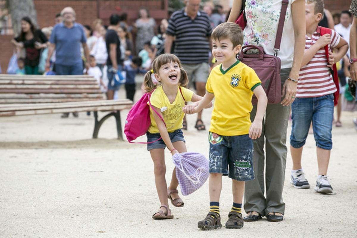 Un niño y una niña ríen en la entrada al colegio.