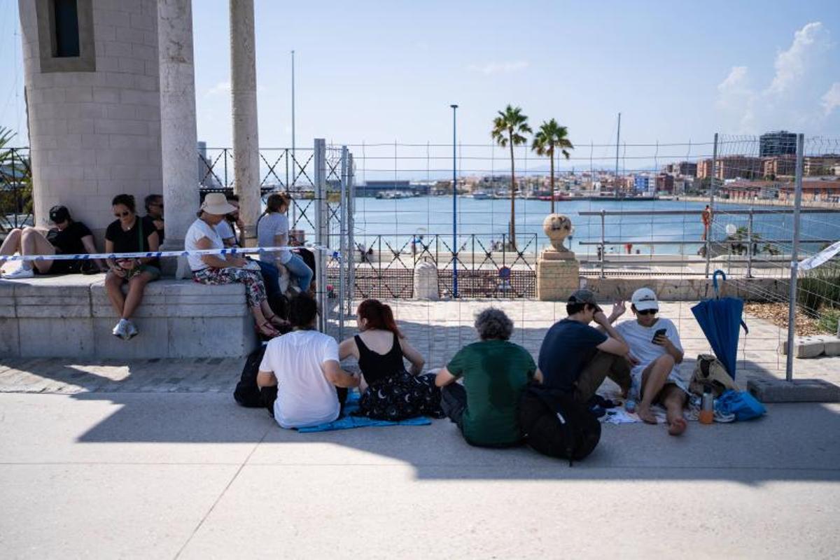 Visitantes y aficionados a la observación astronómica esperan en el Port de la Maria, en Tarragona, para contemplar el eclipse total de Sol.