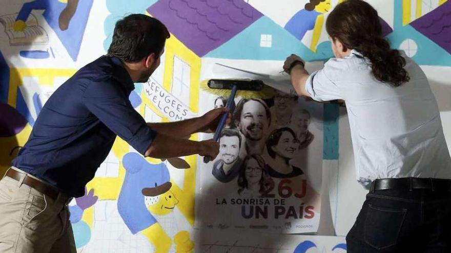 Alberto Garzón a la izquierda, y Pablo Iglesias, pegando el cartel de Unidos Podemos. // Efe