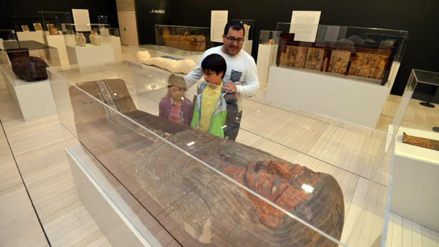 Un padre con sus hijos observan un sarcófago. // G. Santos