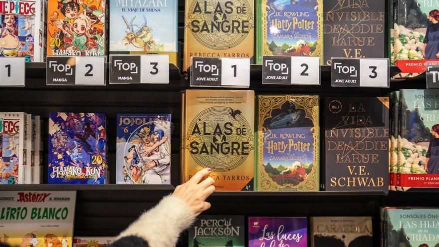 Una persona curiosea los libros de la sección juvenil del Fnac de L'Illa.