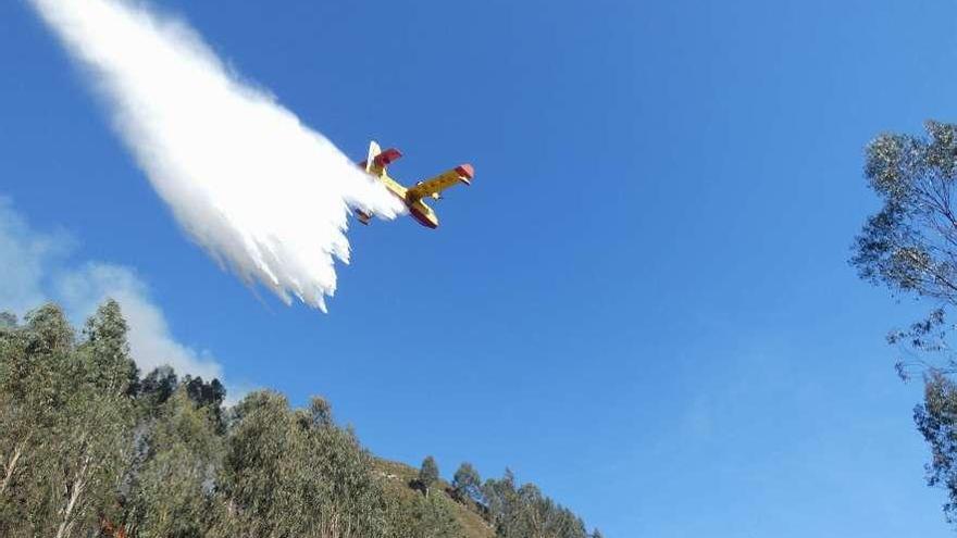 El hidroavión de Medio Ambiente descarga agua sobre uno de los incendios de Llanes.