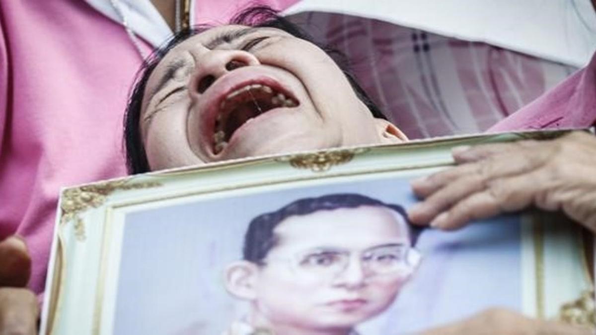 Una mujer llora a las puertas del hospital con la la foto del rey Bhumibol.