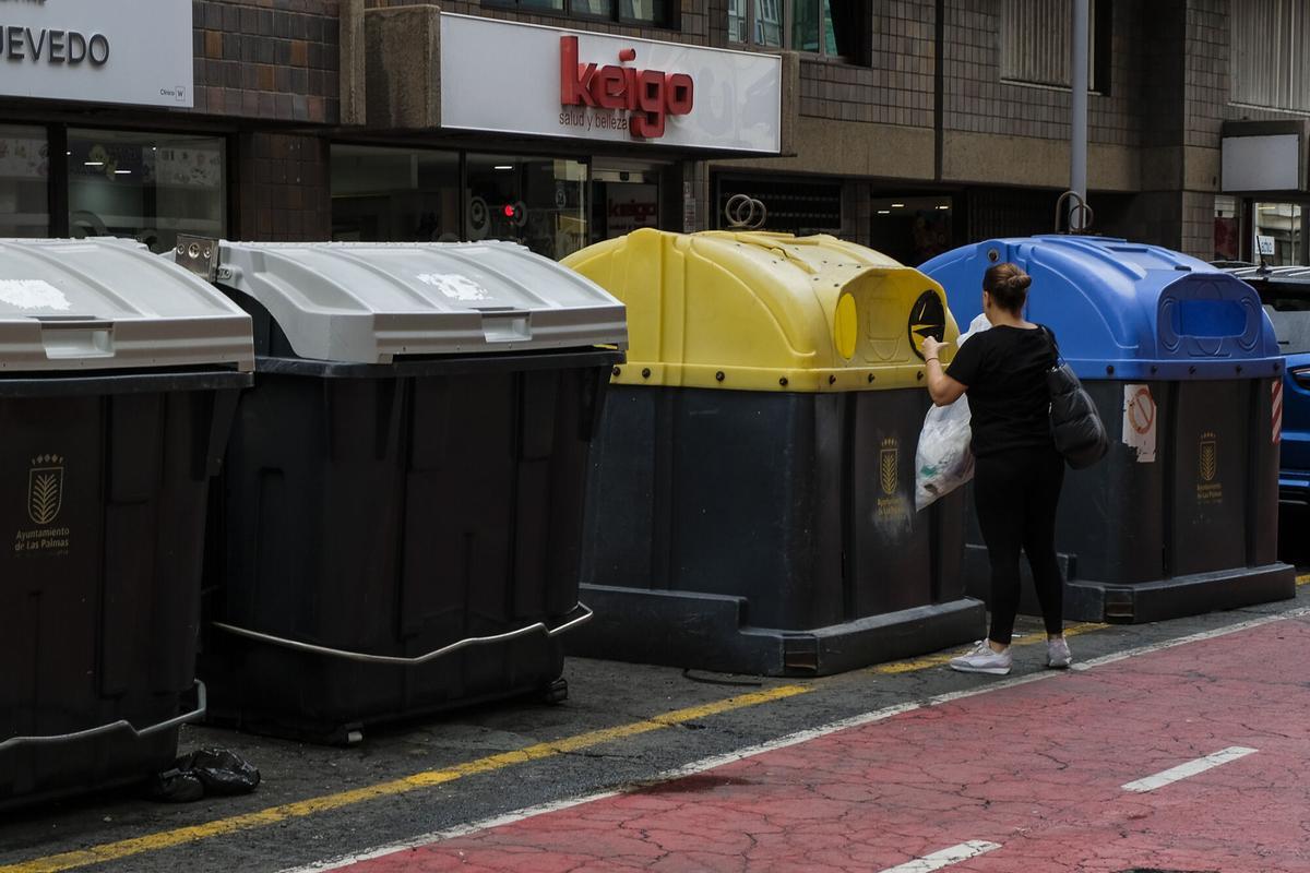 Una mujer tira la basura en un contenerdor de reciclaje la calle Francisco Gourié.
