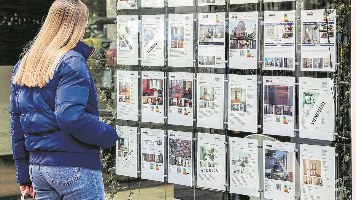 Una mujer mira los anuncios de escaparates en una agencia inmobiliaria.