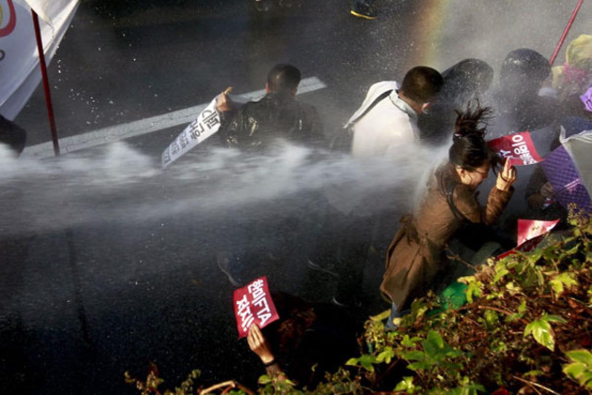 La policia antiavalots llança aigua als participants d’una marxa contra el tractat de lliure comerç de Corea del Sud amb els Estats Units, a Seül (Corea del Sud).
