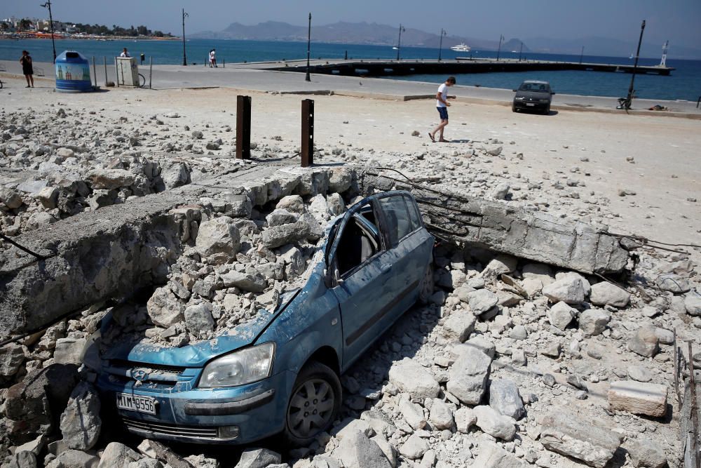 A car is seen under the debris of a collapsed ...